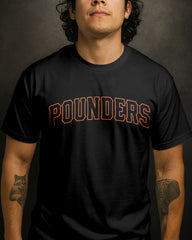 Person wearing a black t-shirt with 'POUNDERS' printed on it against a dark background