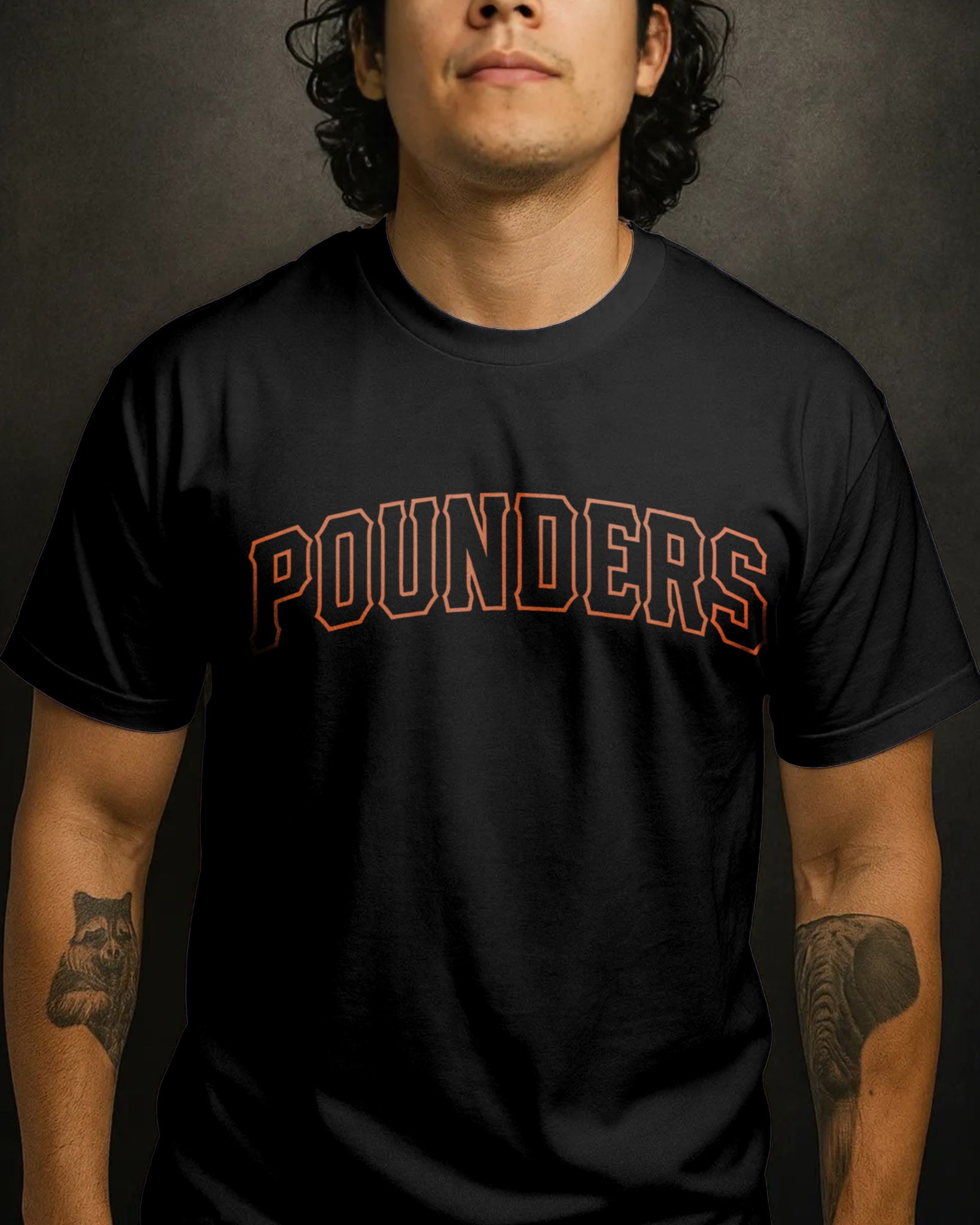 Person wearing a black t-shirt with 'POUNDERS' printed on it against a dark background